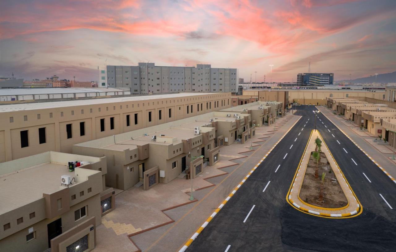 Mirada Gold Jizan - Resort & Private Pools Esterno foto The photo shows a modern residential area with a series of light-colored buildings lined along a road. The architecture appears to be contemporary, featuring low-rise structures that include individual homes or apartments. The street is well-maintain